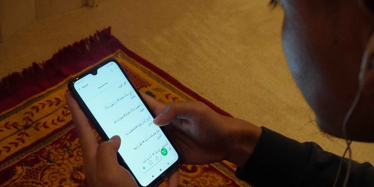 Usai shalat, seorang muslim membaca dan mendengarkan maulid melalui aplikasi KESAN. Foto: Dokumen KESAN