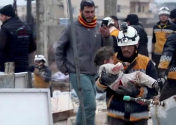 Seorang petugas evakuasi membawa seorang anak yang terluka dari puing-puing sebuah bangunan di Suriah. Foto: news.sky.com