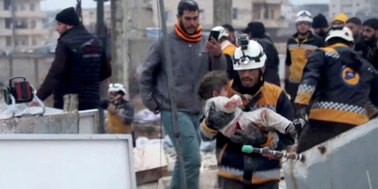 Seorang petugas evakuasi membawa seorang anak yang terluka dari puing-puing sebuah bangunan di Suriah. Foto: news.sky.com
