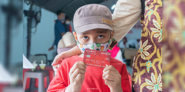 Seorang anak tengah menunjukkan Kartu Pemenuhan Kebutuhan Dasar (PKD) Anak dari Bank DKI. Foto: Bank DKI
