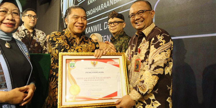 Penjabat Gubernur Banten Al Muktabar menyerahkan piagam penghargaan kepada Kepala Bagian Tata Usaha BPN Banten Osman Affan. Foto : istimewa