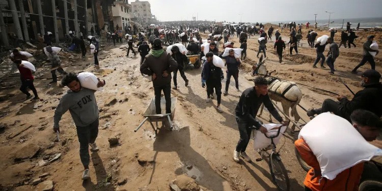 Warga Palestina membawa karung tepung yang mereka ambil dari truk bantuan di Kota Gaza. (Al Jazeera)